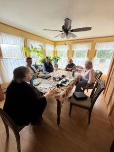 From left: Kim’s sister Karen Dalot, Detective Mike Fitzmorris, Detective Corporal Mike Chavez, Kim’s father Richard Moreau, and Kim’s sister Diane Moreau Levesque sitting at Mr. Moreau’s dining room table for a conversation about Kim’s case as of April 2025.